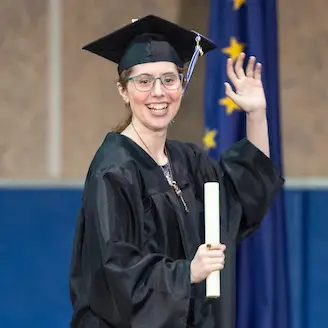 A woman wearing a cap and gown holding a diploma