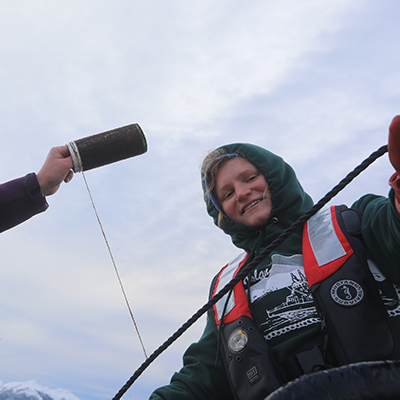 Sara smiles with a coil of kelp spores as the wraps a line at a farm outside the Science Center in Sitka