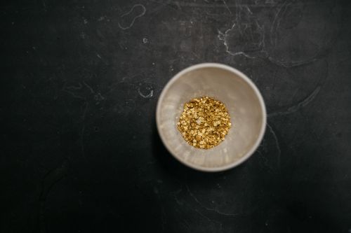 Small white bowl on dark counter with gold inside.