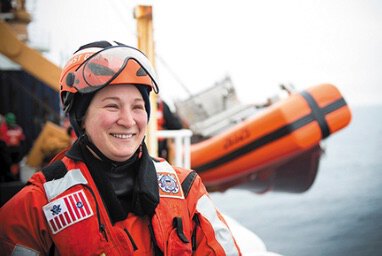 Woman in survival suit looking out at sea